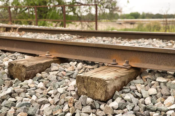 Detail of the wooden sleepers of the rails of a train track surrounded by boulders. Concept trains, tracks, transport, roads.