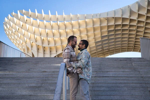 stock image Real marriage of gay couple, looking at each other, hugging, content and happy, leaning on the railing of stairs. Concept lgtb, lgtbiq+, couples, in love, love, hugging.