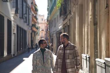 Real marriage of gay couple, walking around the city, holding hands, talking with accomplice attitude. Concept lgtb, lgtbiq+, couples, in love, love.