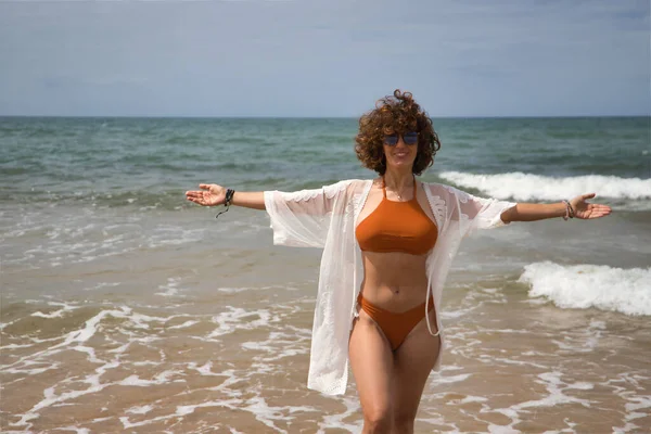 Attractive Mature Woman Curly Hair Sunglasses Bikini Open Arms Grateful — Stockfoto