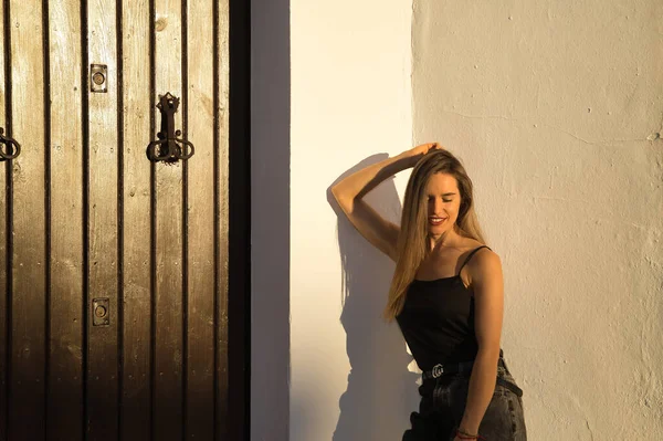 stock image Young woman, beautiful and blonde, with black tank top receiving the last rays of afternoon sun with sensual and provocative attitude. Concept sensuality, provocation, flirting, beauty.