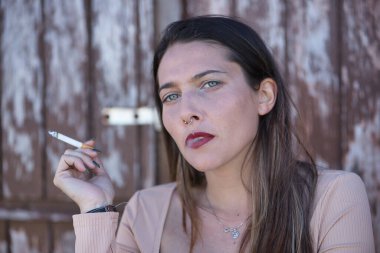 Bir kadın portresi, genç ve çekici, mavi gözlü, sigara içen ve nefes veren bir duman. Kavram tütün, bağımlılık, sağlık.