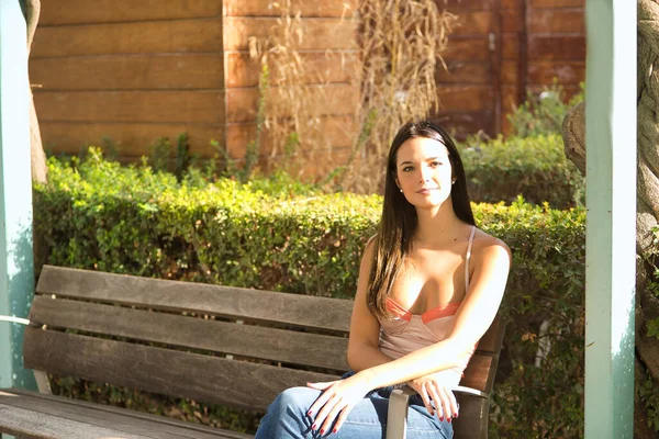 Young Beautiful Woman Straight Brown Hair Orange Top Jeans Sitting — Foto Stock