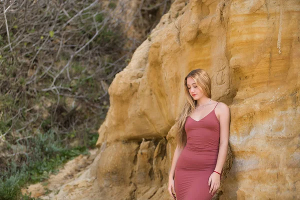 Genç, güzel, pembe elbiseli sarışın bir kadın, taş bir duvara yaslanmış, masumiyet ve şefkatle yere bakıyor. Masumiyet kavramı, şefkat, bekaret..