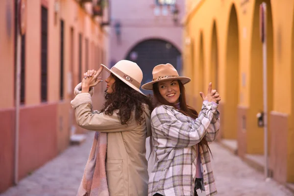 二人の女性 若いと美しい 帽子やコートと 一緒に背中と自分の手で銃の形を作ります 幸せと面白いです コンセプト秋 カップル — ストック写真