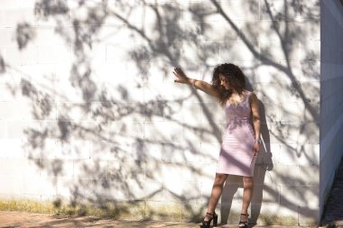 Genç bir kadın, güzel, esmer, kıvırcık saçlı, pembe elbiseli, bir ağacın gölgeleriyle beyaz bir duvara yaslanmış, üzgün, yalnız ve melankolik. Keder kavramı, üzüntü.