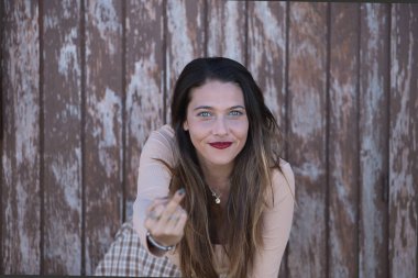 Portrait of a woman, young and attractive, blue eyes, doing the comb in a hooligan plan on a background of wooden boards. Concept portrait, hooligan, nonconformist.