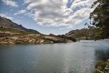 Büyük kayalar ve Atlantik Okyanusu 'ndan gelen bulutlu mavi gökyüzü ile dağlık oluşumlu güzel bir manzara. Manzara konsepti, su, dağlar, bulutlar.