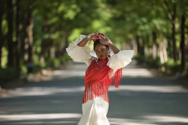 ベージュジプシーのフラメンコスーツと赤いショールの若い黒人と南米の女性は スペインのセビリアの街の公園で踊ります コンセプトダンス フラメンコ アート — ストック写真