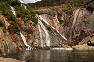 Direk denize akan bir nehirden gelen güzel şelale derin bir kanyon oluşturuyor. Manzara konsepti, su, dağlar, şelaleler.