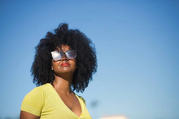 美しい アフロの髪を持つ黒の女性の肖像画 黄色のTシャツとサングラス 太陽を見て リラックスして穏やかな コンセプトの休暇 サングラス — ストック写真