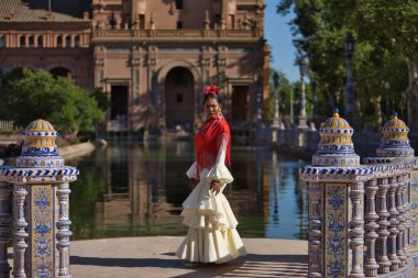 İspanya 'nın Seville şehrinde güzel bir meydanda poz veren bej renkli çingene flamenko takım elbiseli genç siyahi ve Güney Amerikalı kadın. Konsept dansı, folklor, flamenko, sanat.