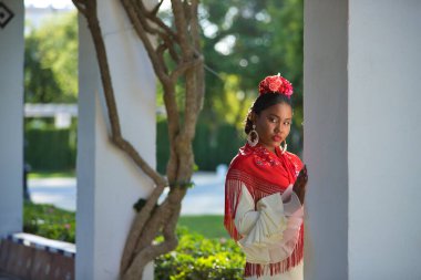 İspanya 'nın Seville şehrindeki bir parkta bej renkli çingene flamenko takım elbiseli ve kırmızı şallı genç siyah ve Güney Amerikalı bir kadının portresi. Konsept dansı, folklor, flamenko, sanat.