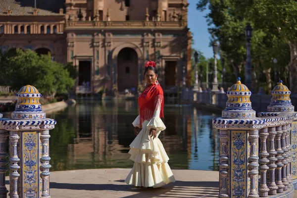 stock image Young black and South American woman in a beige gypsy flamenco suit, posing in a beautiful square in the city of Seville in Spain. Concept dance, folklore, flamenco, art.