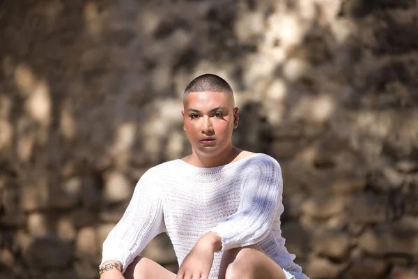 İkili olmayan birinin portresi, genç ve Güney Amerikalı, ağır makyajlı, oturuyor ve kameraya bakıyor. Kavram kraliçesi, lgbtq +, gurur, nonoş.