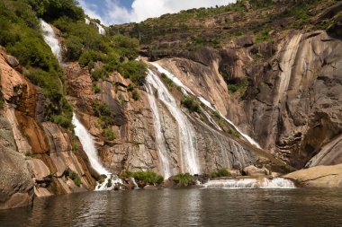 Direk denize akan bir nehirden gelen güzel şelale derin bir kanyon oluşturuyor. Manzara konsepti, su, dağlar, şelaleler.