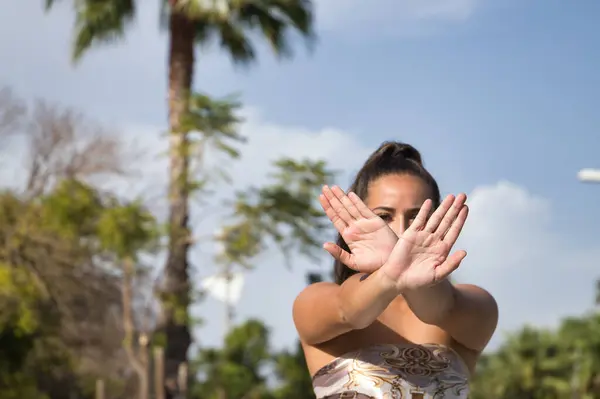 Portrait of Latina and Hispanic girl, young and beautiful, doing modern dance hand movements in the street outdoors. Dance concept, moonwalk, jumpstyle, shuffle, electrodance, hip hop, funky, popping