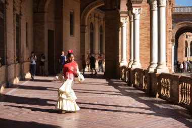 İspanya 'nın Seville şehrinde güzel bir meydanda poz veren bej renkli çingene flamenko takım elbiseli genç siyahi ve Güney Amerikalı kadın. Konsept dansı, folklor, flamenko, sanat.