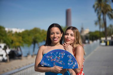 İki genç, güzel ve Güney Amerikalı kadın, esmer ve sarışın, İspanya 'da tatillerinde bir hayranlarıyla tuhaf bir şekilde poz veriyorlar. Güzellik, moda, çiftler, seyahat.