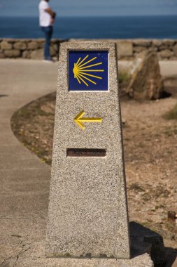 Santiago 'ya giden yolun sıfır kilometresini ok ve kabukla işaretleyen taş mihenk taşı. Hacı kavramı, yol, din, yolculuk.