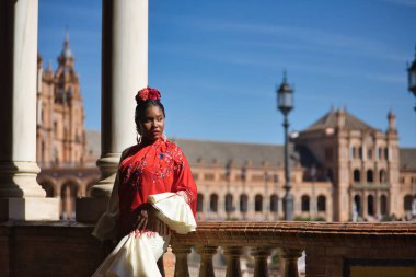 İspanya 'nın Seville şehrinde güzel bir meydanda poz veren bej renkli çingene flamenko takım elbiseli genç siyahi ve Güney Amerikalı kadın. Konsept dansı, folklor, flamenko, sanat.