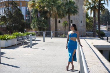 Genç, güzel, esmer, mavi elbiseli ve güneş gözlüklü Güney Amerikalı bir kadın Avrupa 'da seyahat ediyor. Güzellik, moda, trend, seyahat, tatil kavramları.