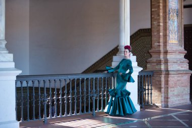 Genç, güzel, sarışın, tipik yeşil renkli flamenko takım elbiseli, demir parmaklıkların yanında poz veriyor. Flamenko konsepti, tipik İspanyolca, Sevilla, Endülüs.