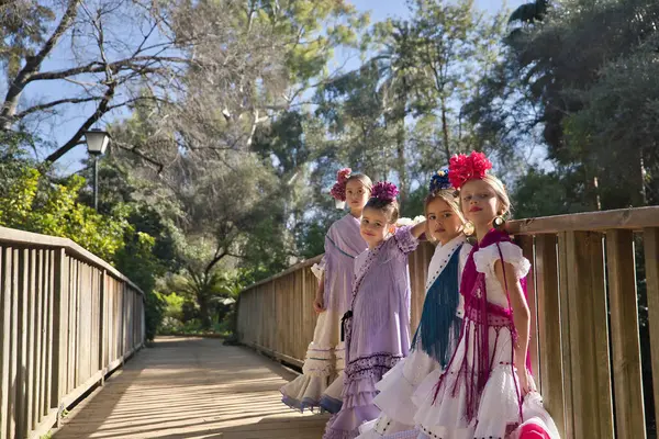 Flamenko yapan dört kız, kameraya bakarak poz veriyorlar, tipik flamenko elbiseler içinde, tahta bir köprüde. Konsept dansı, flamenko, tipik İspanyolca, Sevilla, İspanya.