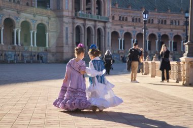 İki kız Flamenko dansı yapıyor ve mutlu bir şekilde konuşuyorlar, sırtları dönük, Sevilla 'da güzel bir meydanda tipik bir flamenko kostümü içinde. Dans konsepti, flamenko, tipik İspanyolca, Sevilla, İspanya.