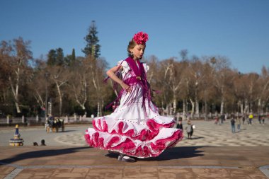 Kız flamenko yapıyor, kostümünü göstermek için kıvırıyor Sevilla 'da güzel bir meydanda, köprüde tipik bir flamenko elbisesi giyiyor. Dans konsepti, flamenko, tipik İspanyolca, Sevilla, İspanya.