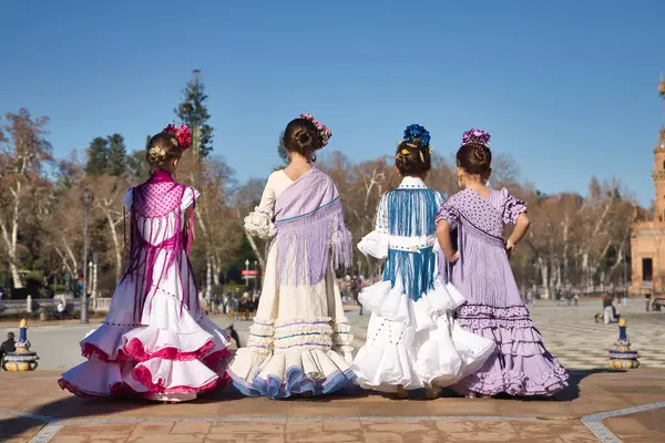 Dört kız Flamenko yapıyor, geriye doğru, tipik flamenko kostümleriyle Sevilla 'da güzel bir meydanda bir köprüde. Dans konsepti, flamenko, tipik İspanyolca, Sevilla, İspanya.