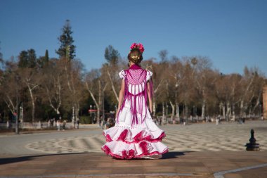 Kız flamenko yapıyor, sırt üstü poz veriyor, Sevilla 'da güzel bir meydanda köprüde tipik flamenko elbisesi giyiyor. Dans konsepti, flamenko, tipik İspanyolca, Sevilla, İspanya.