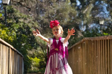 Flamenko yapan, sabun köpüğüyle oynayan, tipik flamenko elbisesiyle tahta bir köprüde dans eden bir kız. Konsept dansı, flamenko, tipik İspanyolca, Sevilla, İspanya.