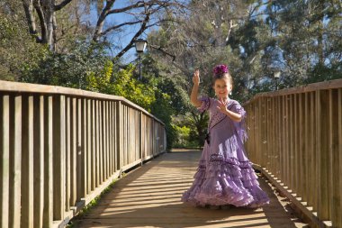 Flamenko yapan, sabun köpüğüyle oynayan, tipik flamenko elbisesiyle tahta bir köprüde dans eden bir kız. Konsept dansı, flamenko, tipik İspanyolca, Sevilla, İspanya.