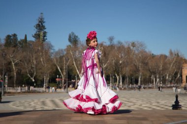 Flamenko yapan, sırtında poz veren, tipik bir flamenko kostümüyle Seville 'deki güzel bir meydanda köprüde. Dans konsepti, flamenko, tipik İspanyolca, Sevilla, İspanya.