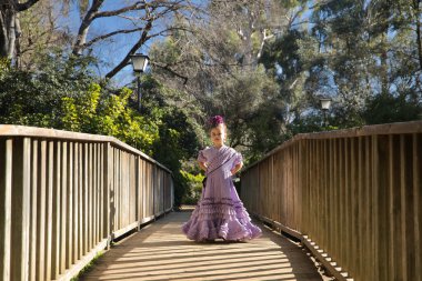 Flamenko yapan bir kız, kameraya bakarak poz veriyor, tipik flamenko elbisesiyle, ahşap bir köprüde. Konsept dansı, flamenko, tipik İspanyolca, Sevilla, İspanya.