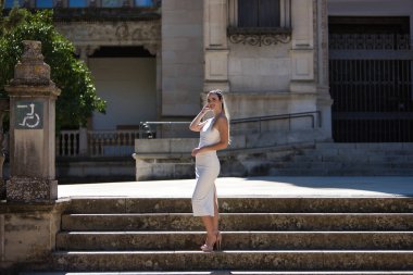 Beyaz takım elbiseli, topuklu ayakkabı giyen, kendine güvenen, kendine güvenen genç, güzel, sarışın bir kadın. Güzellik, moda, moda, model konsepti.