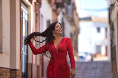 Zarif kırmızı elbiseli, genç, güzel esmer kadın, saçlarına dokunurken yürüyordu, şafak vakti güzel beyaz Endülüs köyünün ıssız bir sokağında. Güzelliği, modayı, trendi, seyahati kavra.
