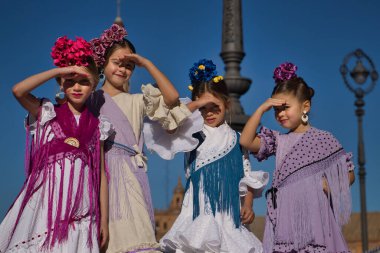 Flamenko yapan dört kız, Seville 'deki güzel bir meydanda, tipik flamenko kostümleriyle gözlerini güneşten koruyorlar. Dans konsepti, flamenko, tipik İspanyol..