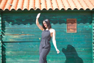 Beyaz benekli siyah elbiseli, genç, güzel bir kadın. Kendini güneşten koruyor. Bağımsız ve güçlü. Bağımsızlık kavramı, güç, güzellik, moda.