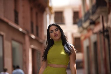 Genç, güzel, esmer, yeşil takım elbiseli, başarılı, özgür ve bağımsız bir kadın kılığında Latin bir kadının portresi. Güzelliği, modayı, eğilimi, şehri kavra.