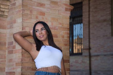 Faslı bir kadının portresi, genç, güzel, esmer, beyaz bluzlu, rüya gibi görünüşlü, duvara yaslanmış. Etnik köken, çeşitlilik, kadınlık, güzellik kavramları.