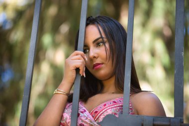 Faslı bir kadının portresi, genç, güzel, esmer, kaşmir bir elbise giymiş, üzgün, yalnız, toplumun baskılarına dayanan, bir çite yapışan. Etnik köken, kimlik kavramı.