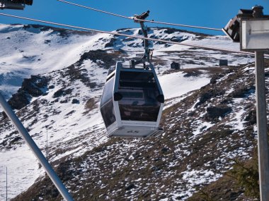 Kayak merkezinin tepesine giden teleferik asansörleri. Böylece kayakçılar ve snowboardcular yamaçtan inmeye başlayabilecekler. Karı, sporu, tatil köyünü, kışı.