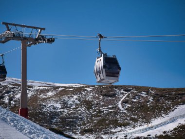 Kayak merkezinin tepesine giden teleferik asansörleri. Böylece kayakçılar ve snowboardcular yamaçtan inmeye başlayabilecekler. Karı, sporu, tatil köyünü, kışı.