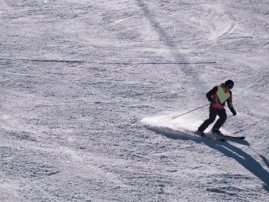 Kayakçı güneşli bir kış gününde bir tatil köyünde kayak pistinde spor yapıyor. Kar, spor, mevsim, kış kavramları.