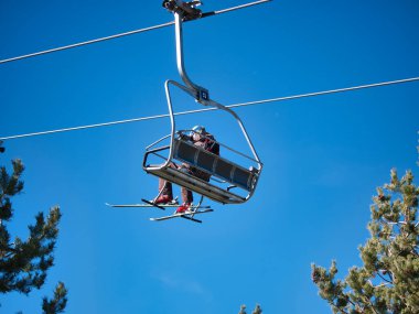 Kayakçılar ve snowboardcular yamaçtan inmeye başlayabilsinler diye kayak merkezinin tepesine giden sandalyeler. Karı, sporu, tatil köyünü, kışı.
