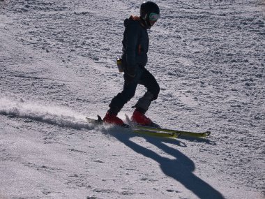Kayakçı güneşli bir kış gününde bir tatil köyünde kayak pistinde spor yapıyor. Kar, spor, mevsim, kış kavramları.