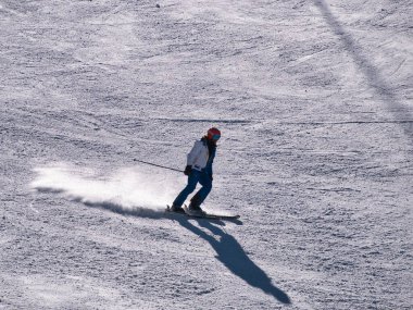 Kayakçı güneşli bir kış gününde bir tatil köyünde kayak pistinde spor yapıyor. Kar, spor, mevsim, kış kavramları.