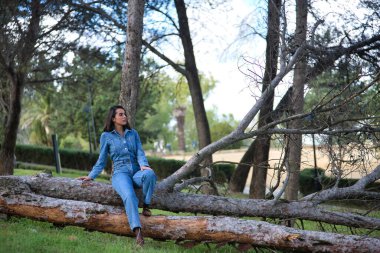 Genç, güzel, esmer, İspanyol bir kadın. Kot pantolon giyiyor. Dalgın ve dalgın. Kavram moda, güzellik, moda, kadınlık.